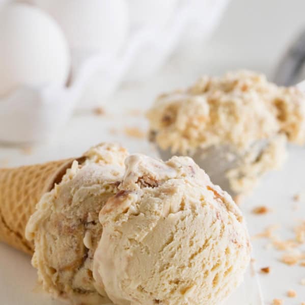 Ice cream cone with salted caramel ice cream with fudge and toasted coconut on it's side.
