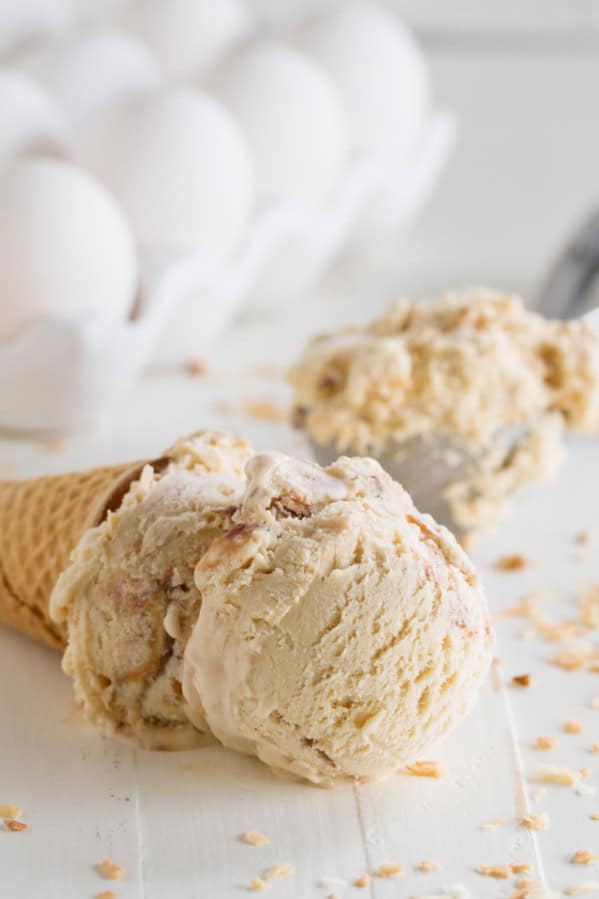 Ice cream cone with salted caramel ice cream with fudge and toasted coconut on it's side.