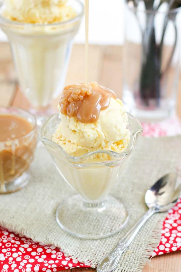 Pouring homemade salted caramel sauce over the top of sweet corn ice cream in a glass cup.