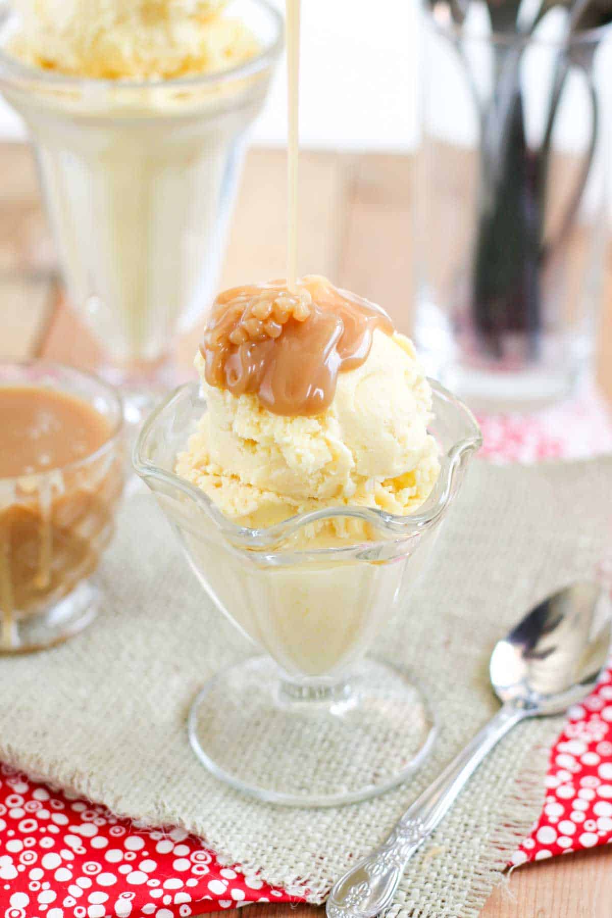 Pouring homemade salted caramel sauce over the top of sweet corn ice cream in a glass cup.