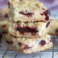 Three Cranberry Cheesecake Bars stacked on top of each other.