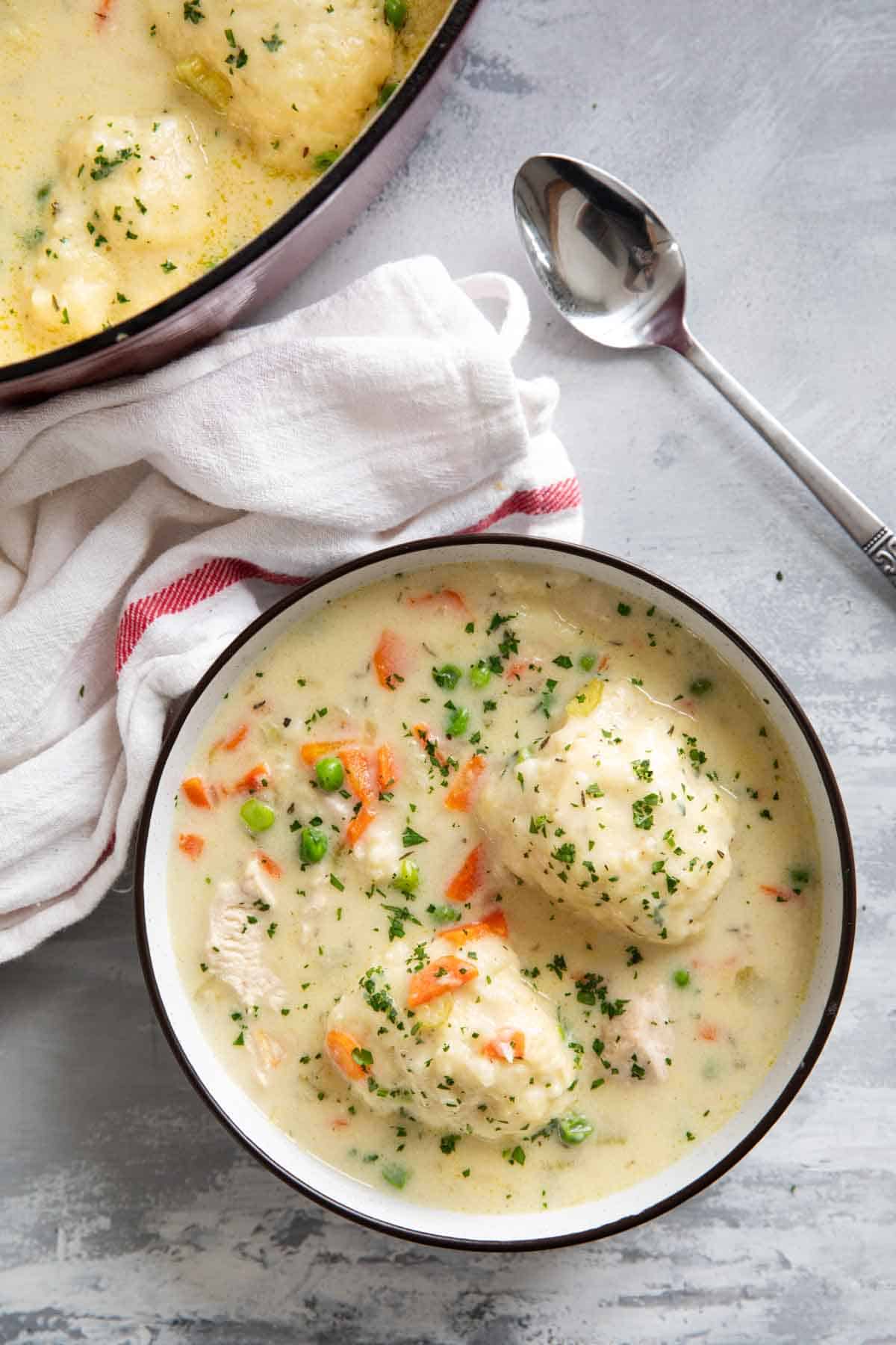Bowl of chicken and dumplings topped with fresh herbs.