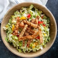 Wooden bowl filled with Asian Chopped Salad topped with fried wonton strips.