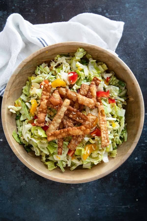 Wooden bowl filled with Asian Chopped Salad topped with fried wonton strips.