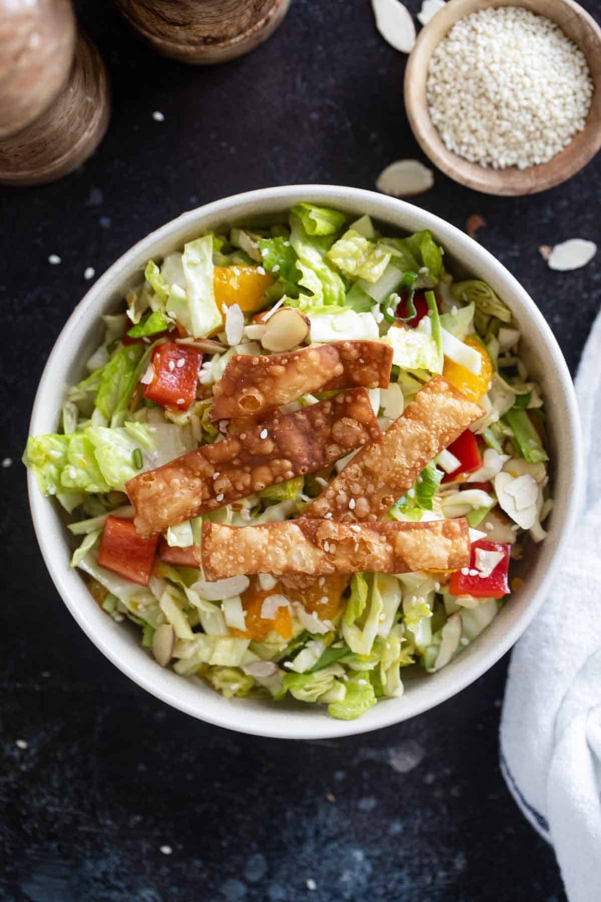 Bowl filled with Asian Chopped Salad topped with fried wonton strips.