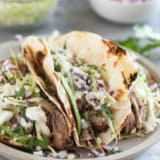 Shredded Pork Tacos topped with cabbage, onions, avocado, and more.