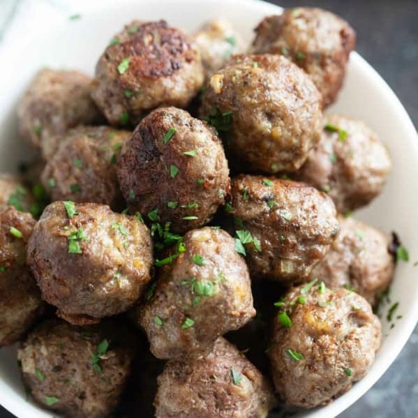 Baked meatballs in a bowl sprinkled with parsley.