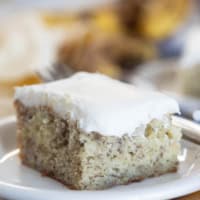 Slice of Banana Cake with Cream Cheese Frosting on a small plate.