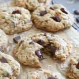 Chocolate Chunk Oatmeal Coconut Cookies on a cooling rack, with one cookie broken in half.