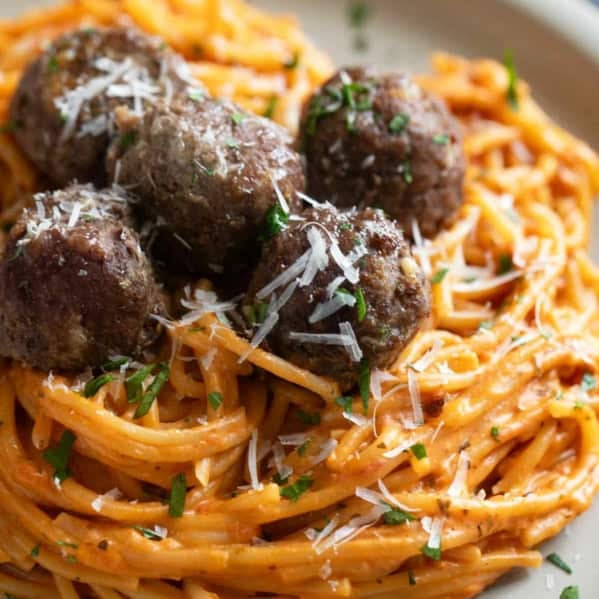 Creamy One Pot Spaghetti topped with baked meatballs, parsley, and parmesan cheese.