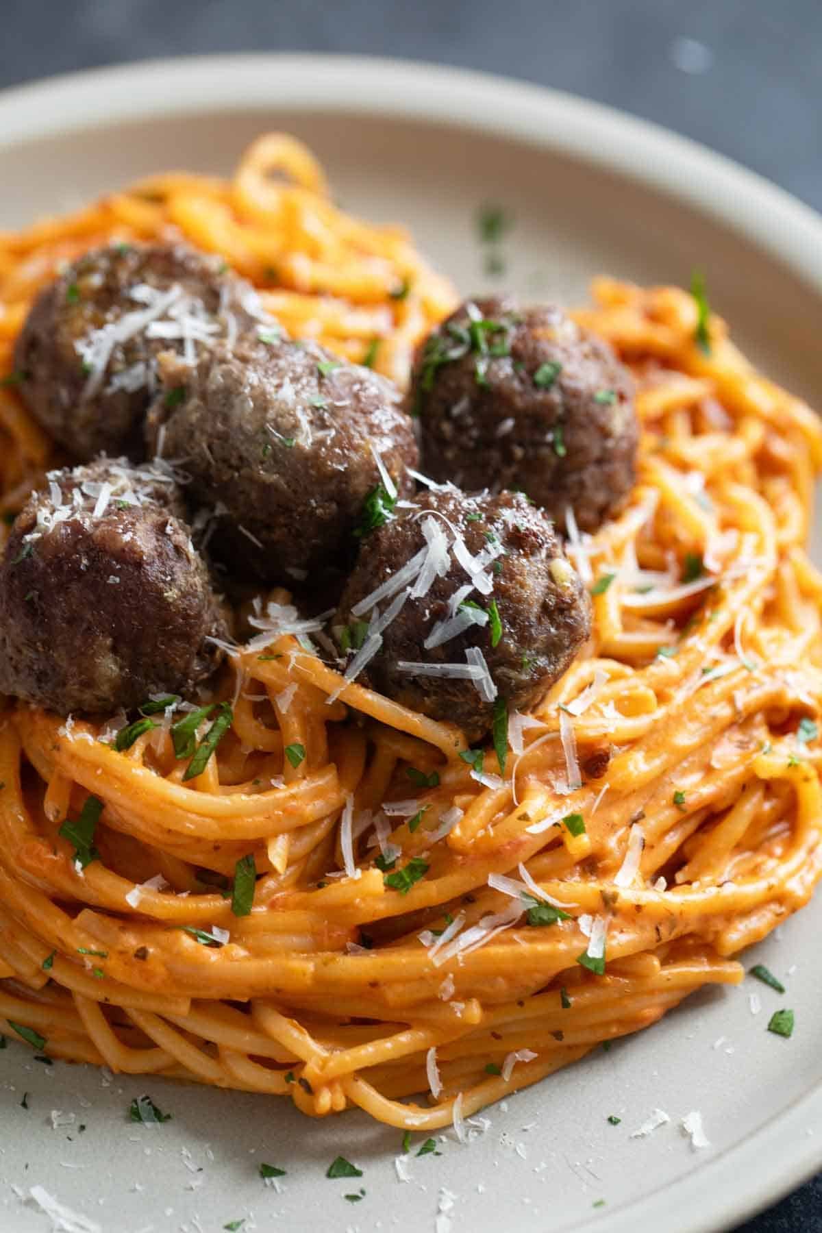 Creamy One Pot Spaghetti topped with baked meatballs, parsley, and parmesan cheese.