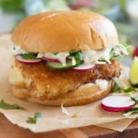 Crispy Fish Sandwich topped with cucumber, radish, cabbage, and homemade wasabi tartar sauce.