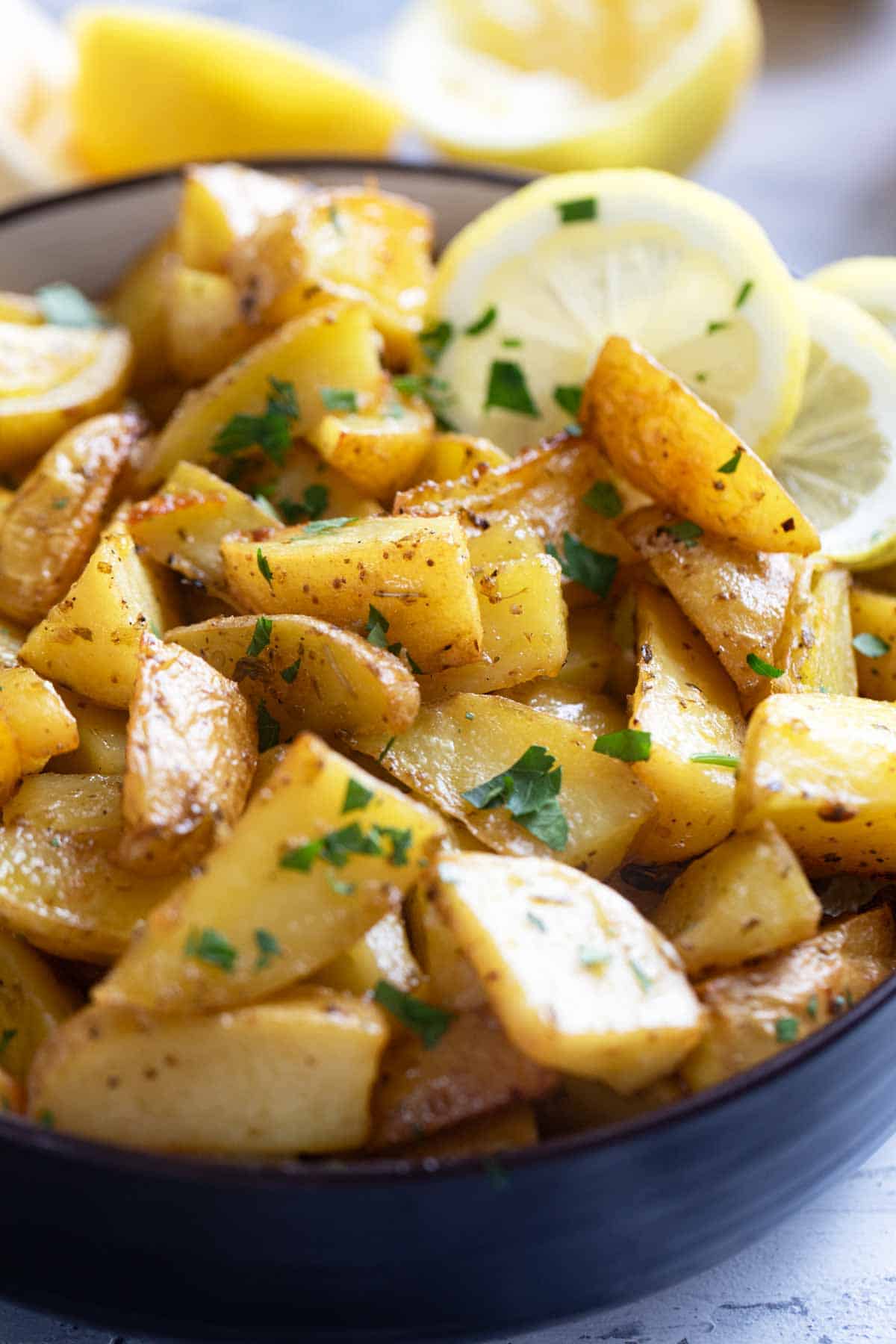 Bowl filled with Greek Lemon Potatoes sprinkled with parsley.