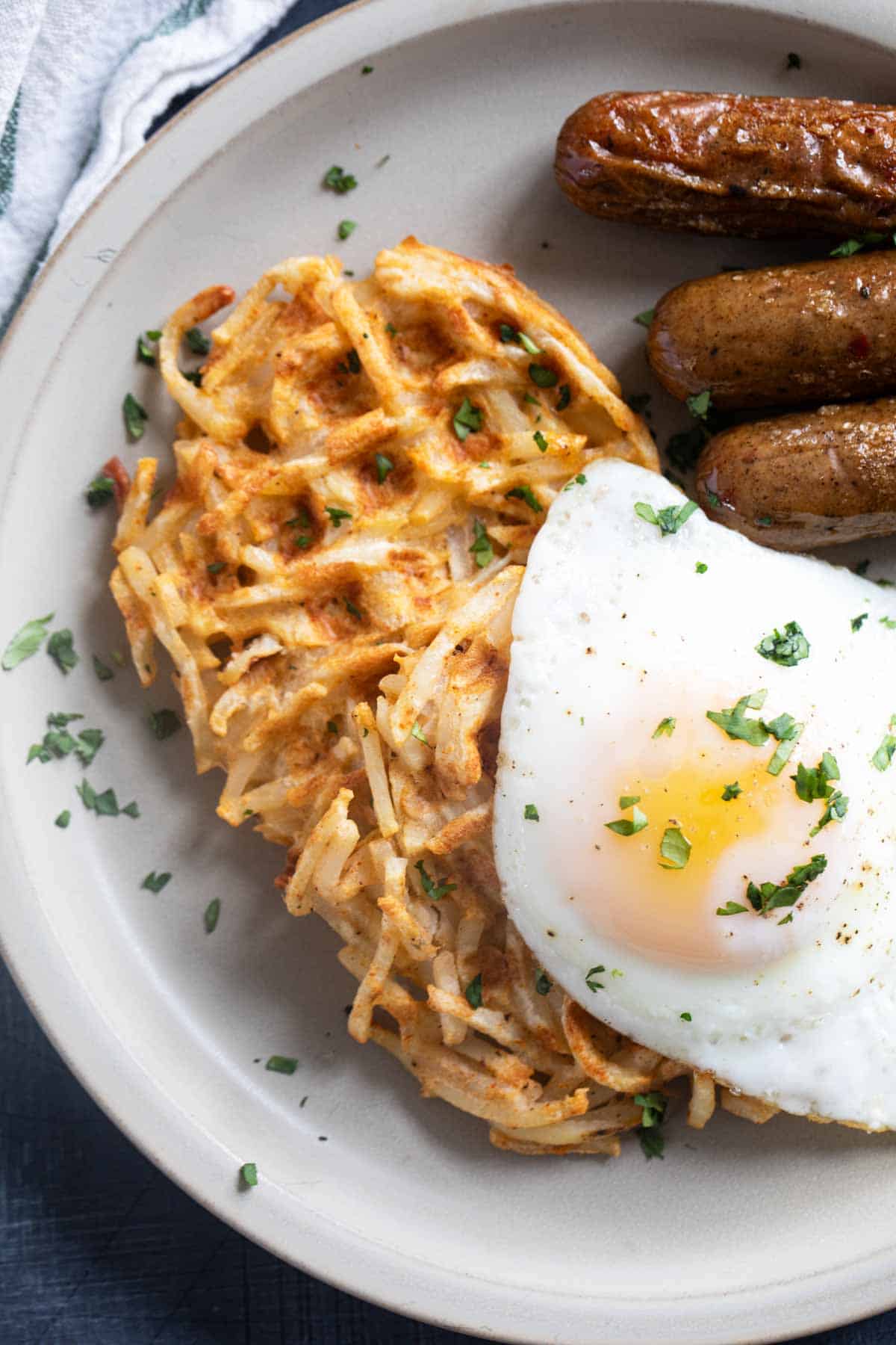 Two hash brown waffles with an over easy egg on top.