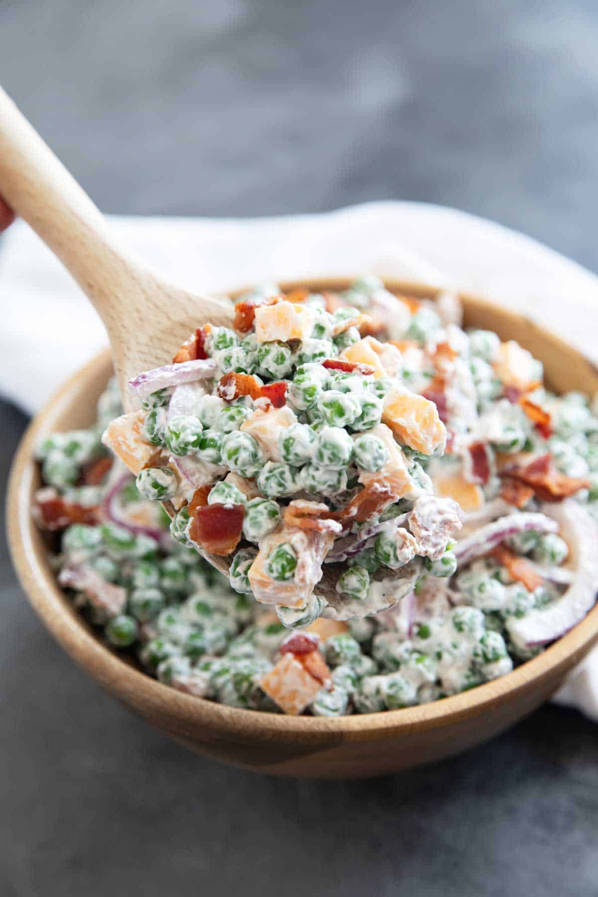 Large spoonful of pea salad over the bowl of salad.
