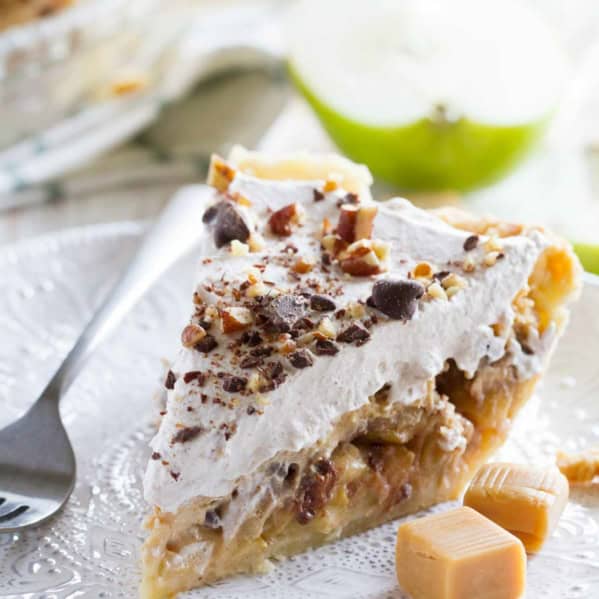 Slice of Taffy Apple Cheesecake Pie on a plate with pieces of caramel.