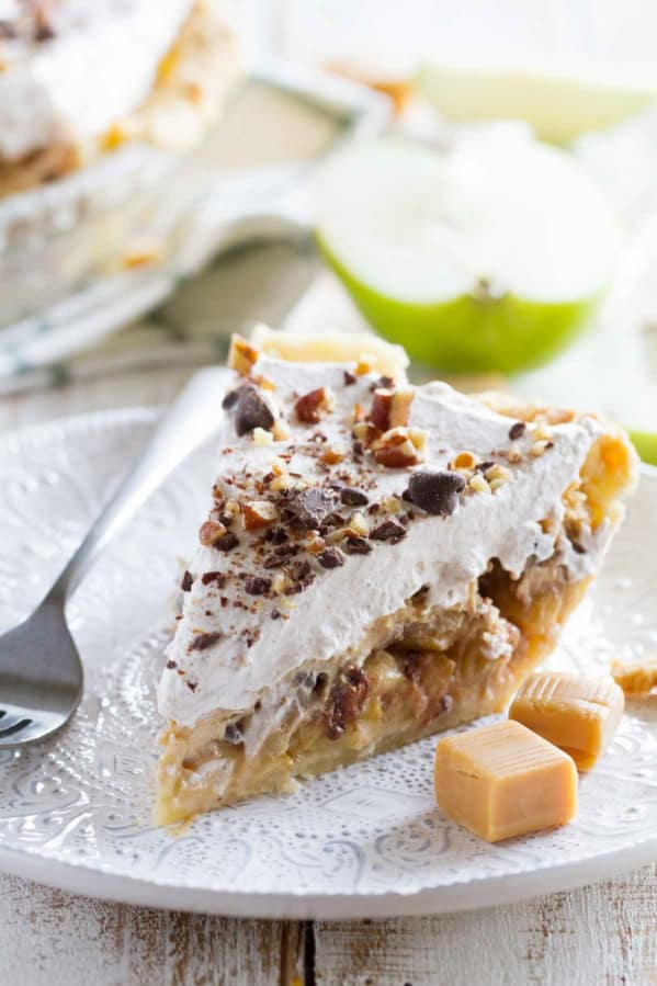 Slice of Taffy Apple Cheesecake Pie on a plate with pieces of caramel.