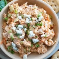 Wooden bowl filled with Buffalo Chicken Salad topped with crumbled blue cheese.