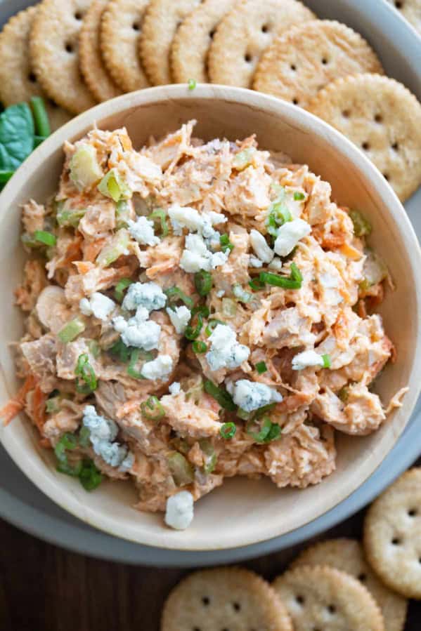 Wooden bowl filled with Buffalo Chicken Salad topped with crumbled blue cheese.