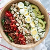 Cobb Salad with toppings arranged in lines on top in a large bowl.