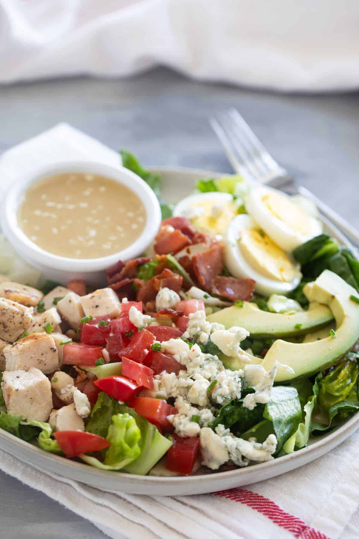 Cobb Salad on a plate with ramekin of dressing on the plate.