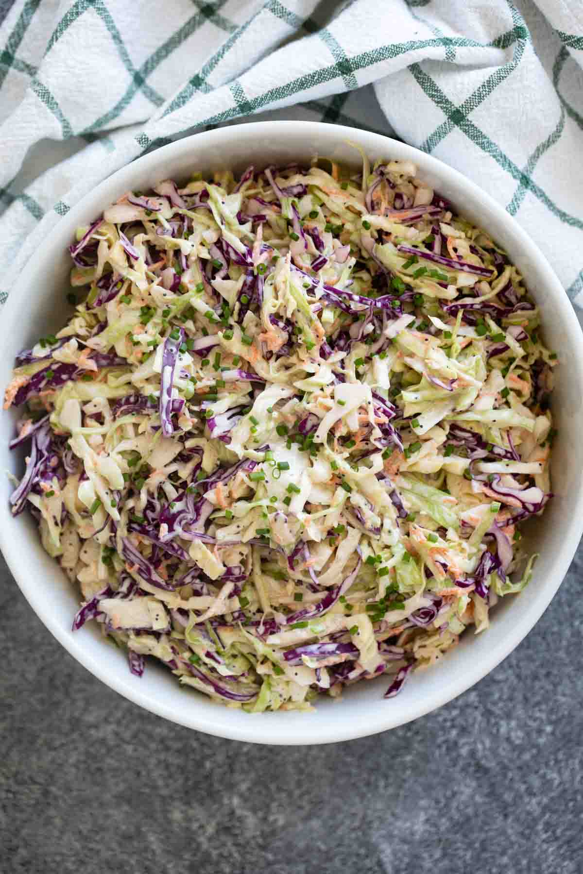 Large bowl filled with coleslaw with poppy seeds.