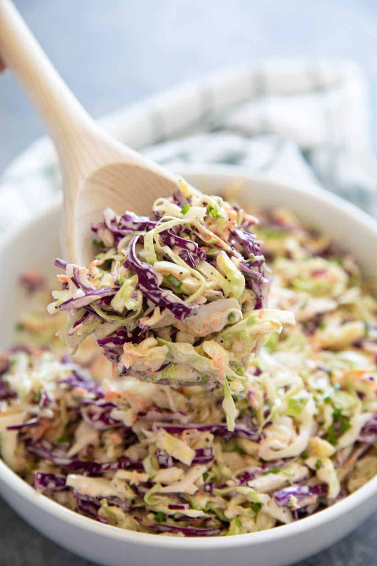 Wooden spoon full of coleslaw.