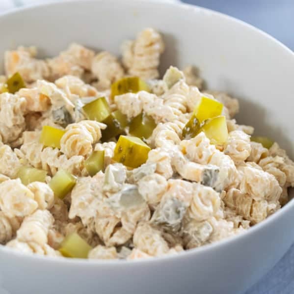 Serving bowl filled with Dill Pickle Pasta Salad topped with chopped pickles.
