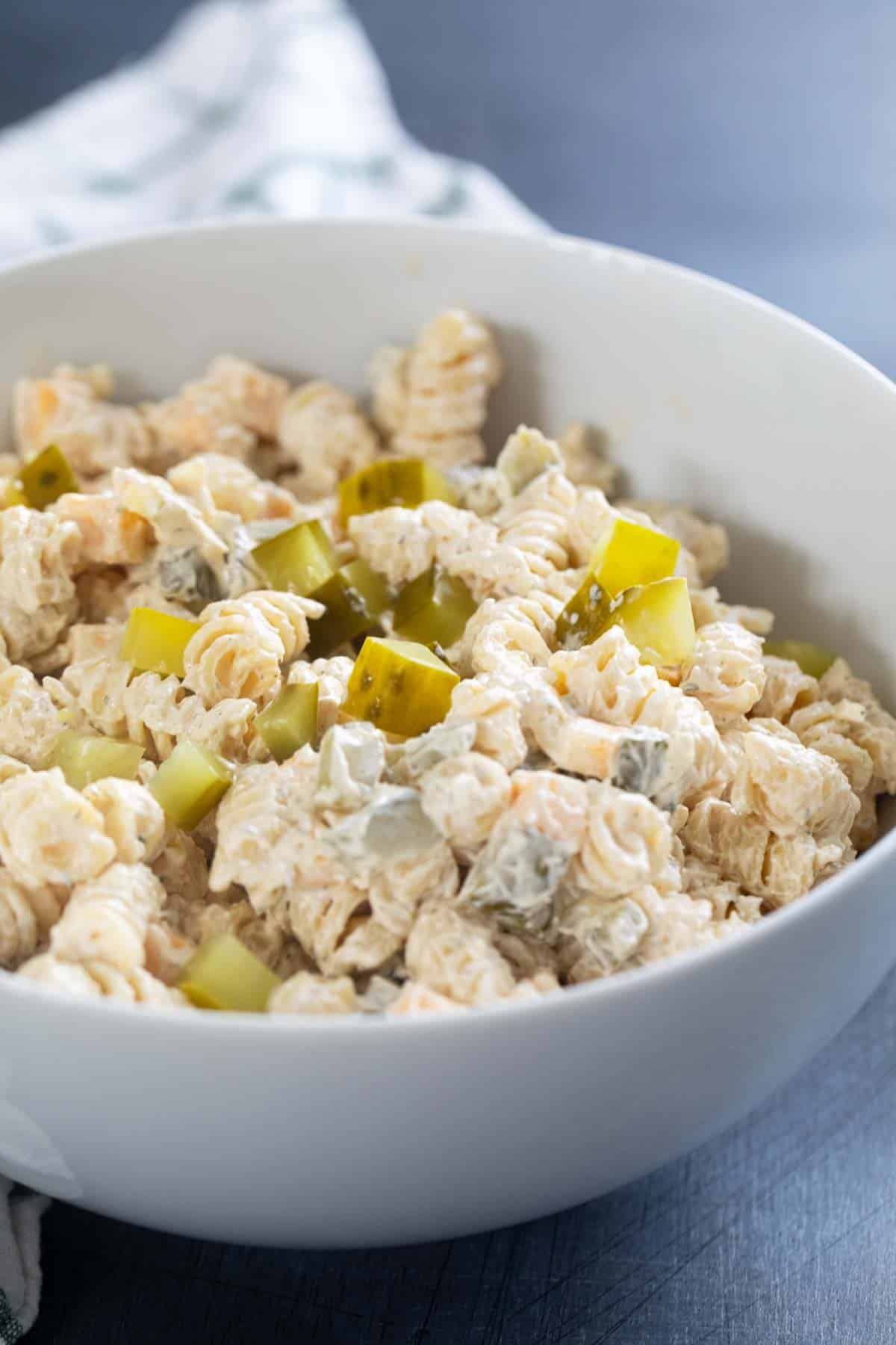 Serving bowl filled with Dill Pickle Pasta Salad topped with chopped pickles.