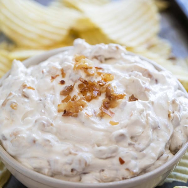 Bowl of French Onion Dip surrounded by potato chips.