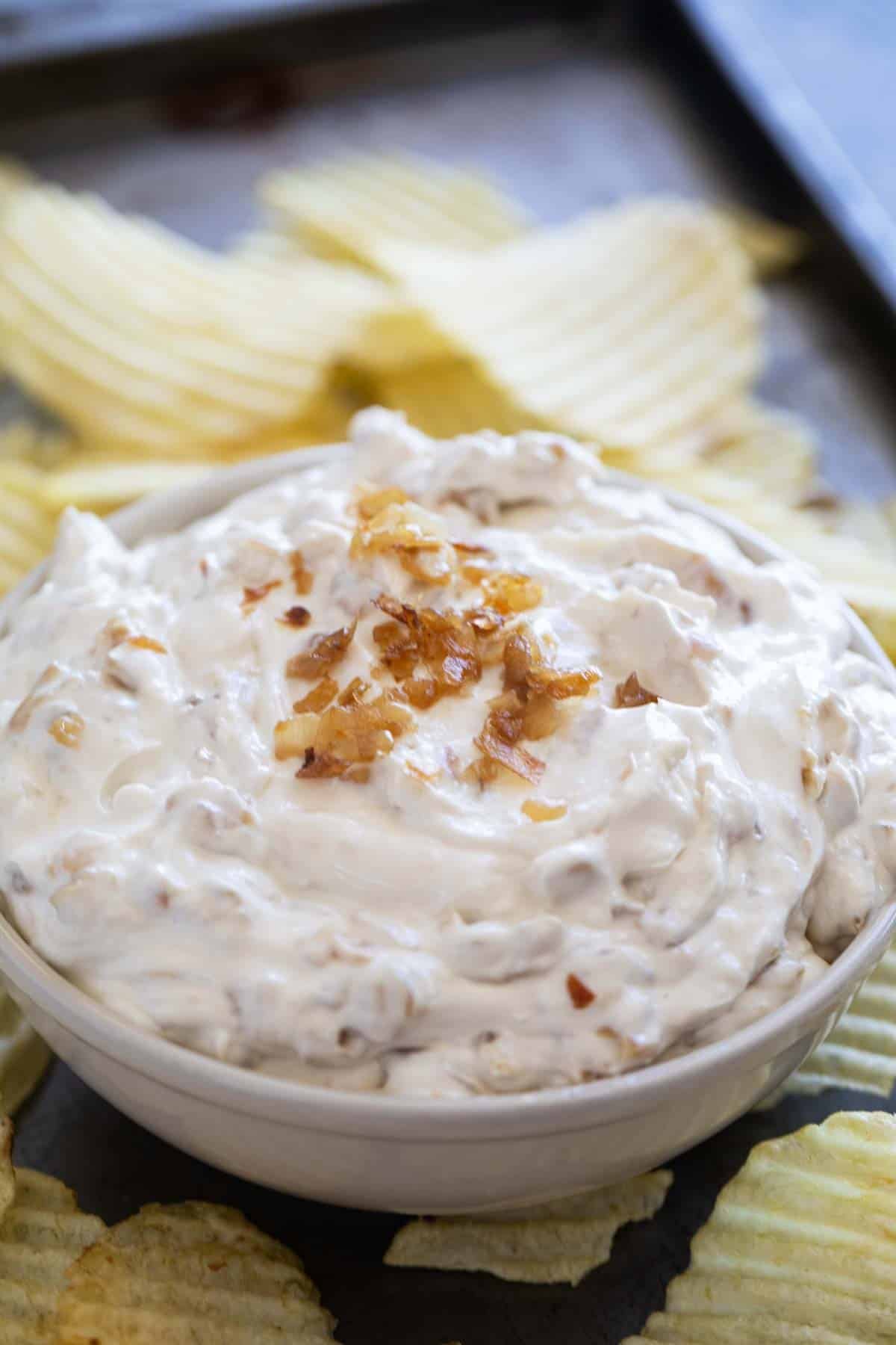 Bowl of French Onion Dip surrounded by potato chips.