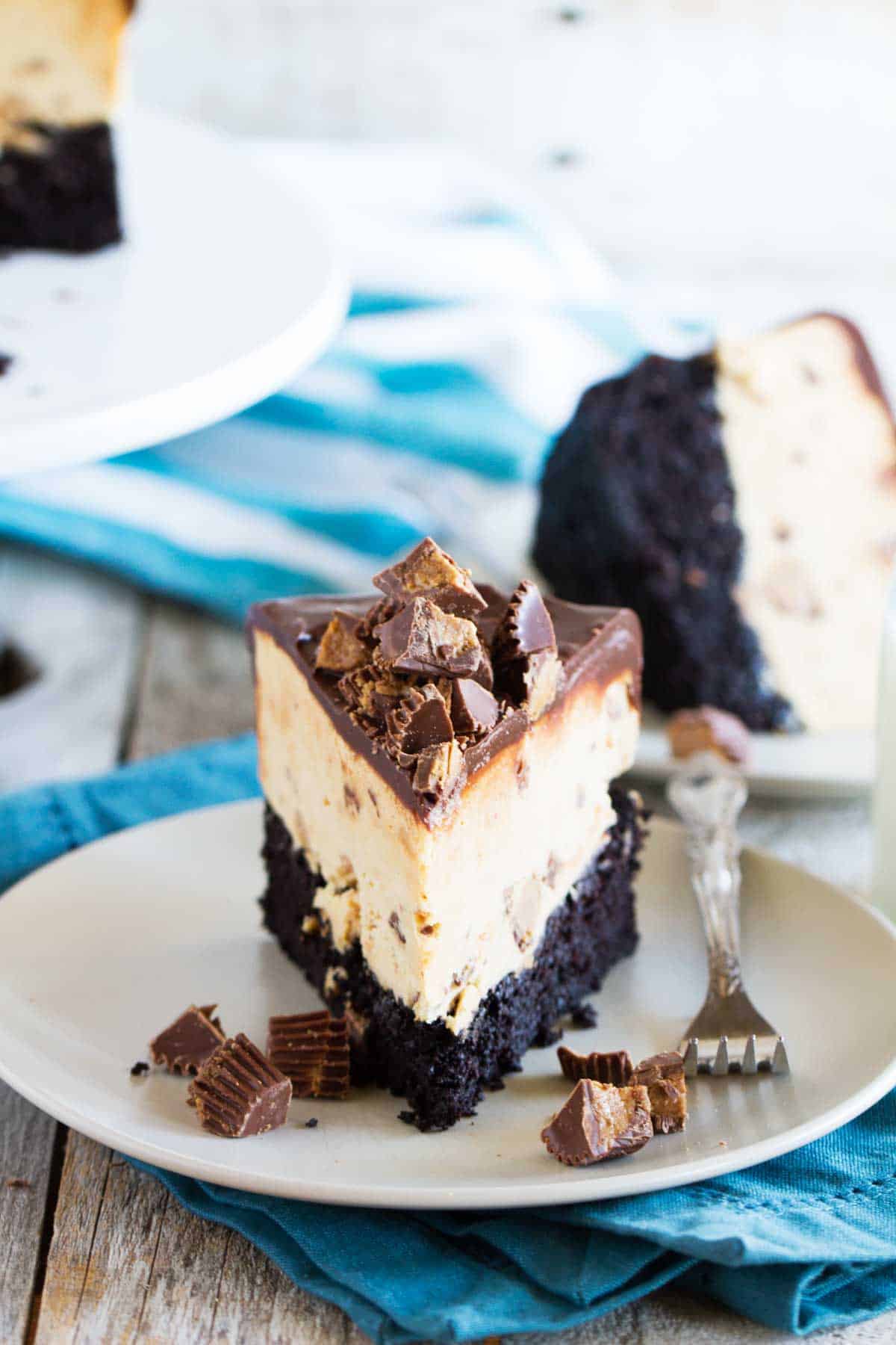 Slice of peanut butter ice cream cup on a plate with chunks of peanut butter cups on top and on the sides.