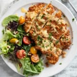 Pretzel Crusted Chicken with Mustard Cheddar Sauce with a side salad on a plate.
