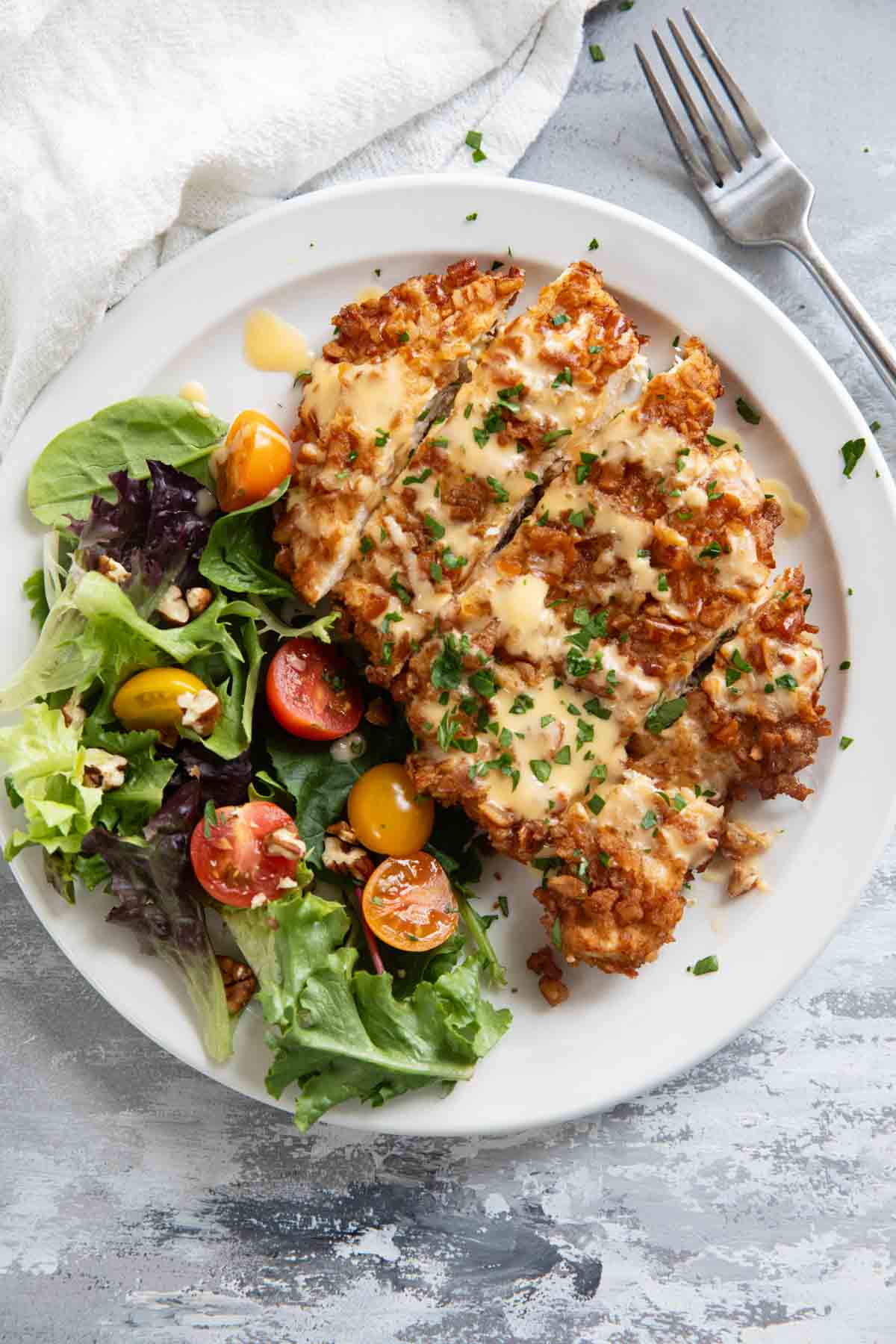 Pretzel Crusted Chicken with Mustard Cheddar Sauce with a side salad on a plate.