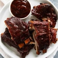 Plate full of bbq slow cooker ribs with a bowl of bbq sauce.