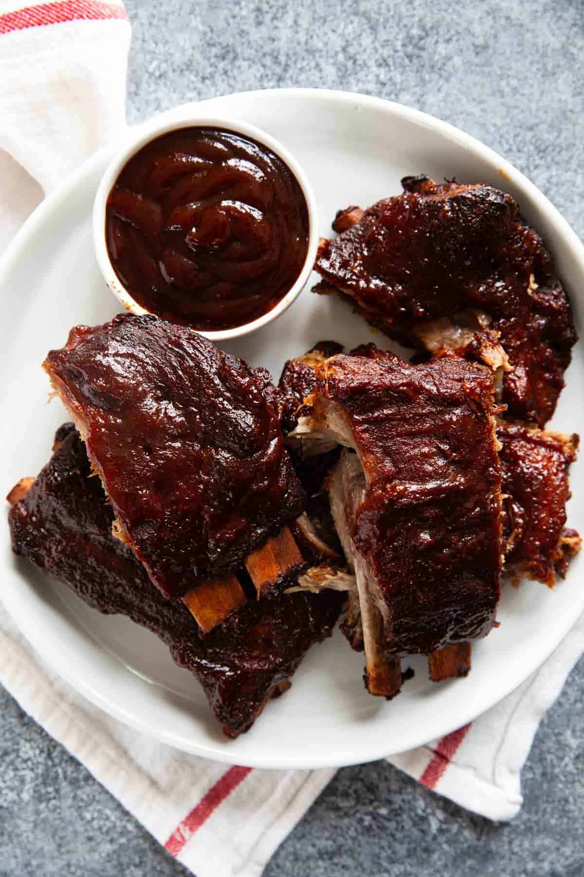 Plate full of bbq slow cooker ribs with a bowl of bbq sauce.