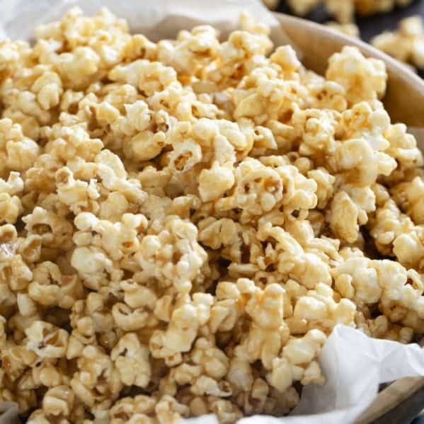 Large wooden bowl filled with soft caramel popcorn.