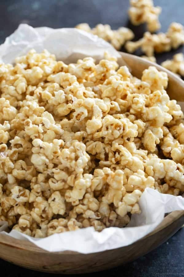 Large wooden bowl filled with soft caramel popcorn.