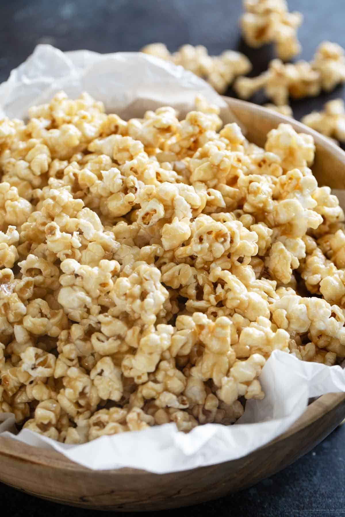 Large wooden bowl filled with soft caramel popcorn.