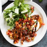 Bruschetta Chicken on a plate drizzled with balsamic vinegar.