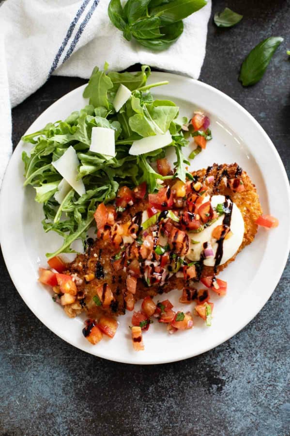 Bruschetta Chicken on a plate drizzled with balsamic vinegar.