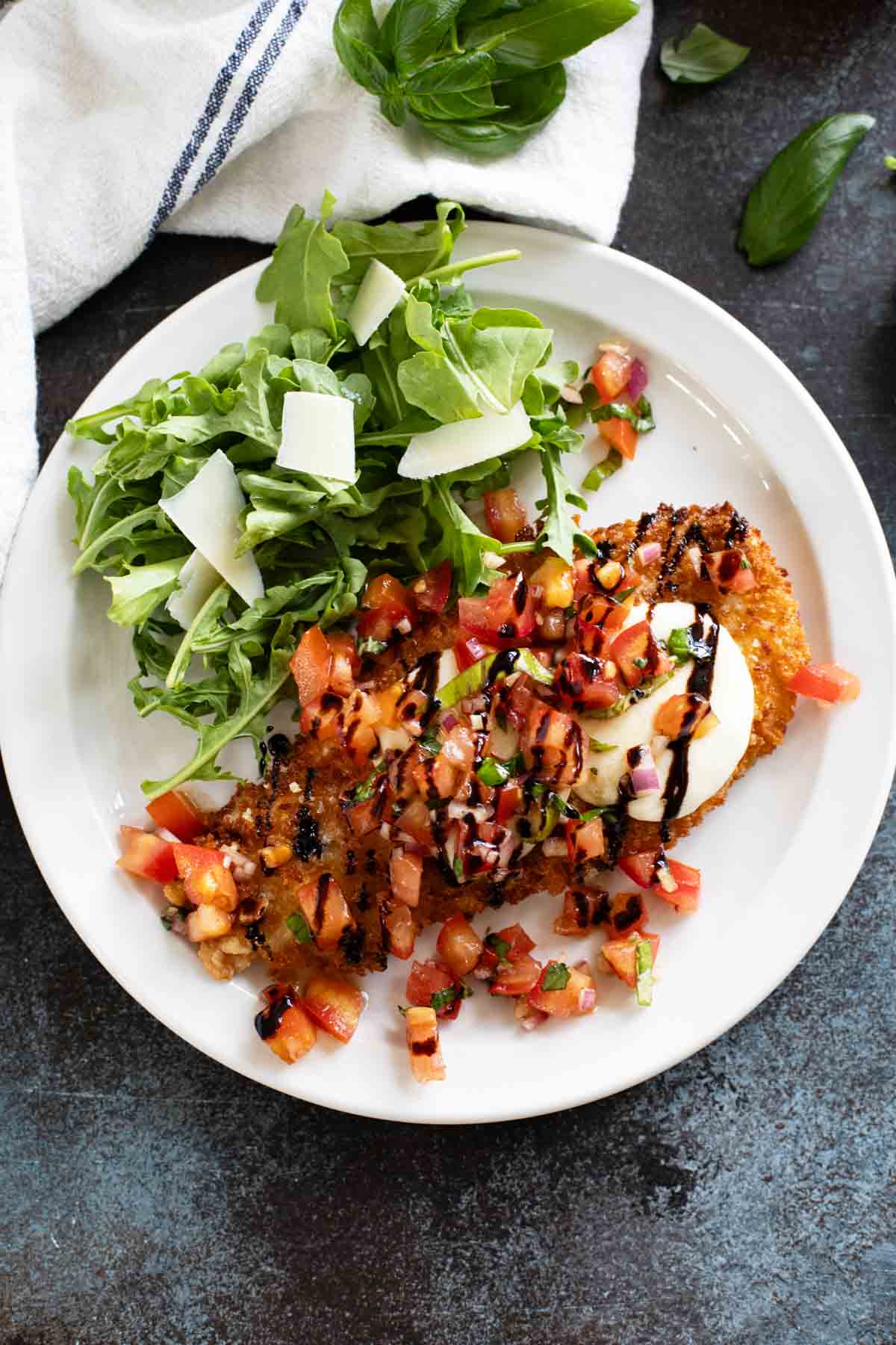 Bruschetta Chicken on a plate drizzled with balsamic vinegar.