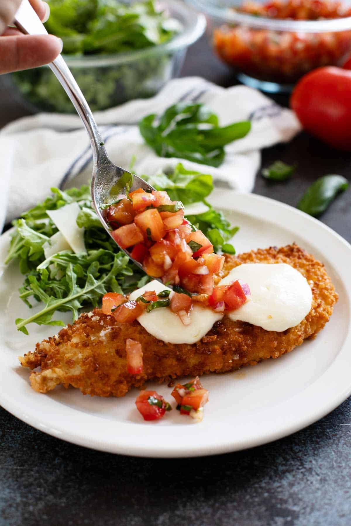 Adding tomato topping to Bruschetta Chicken.