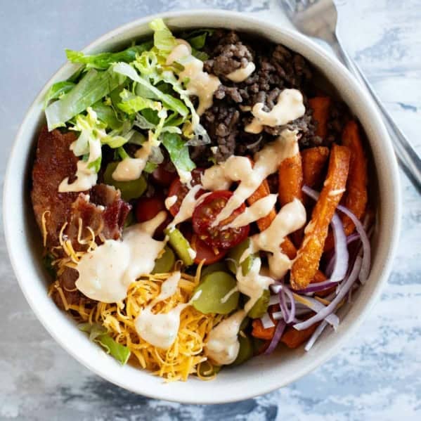 Burger Bowls with beef, sweet potato fries, onions, tomatoes, cheese, bacon, and more.