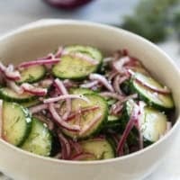 Bowl with Cucumber Onion Salad with fresh dill and salt and pepper.