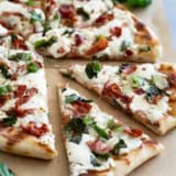 Slices of Grilled White Pizza with Bacon and Basil with more fresh basil on the side.