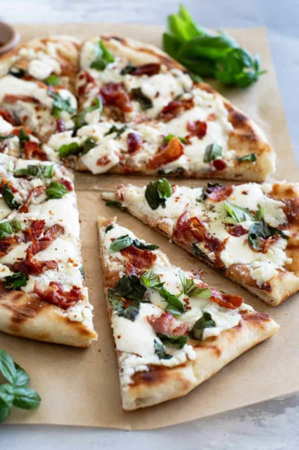 Slices of Grilled White Pizza with Bacon and Basil with more fresh basil on the side.