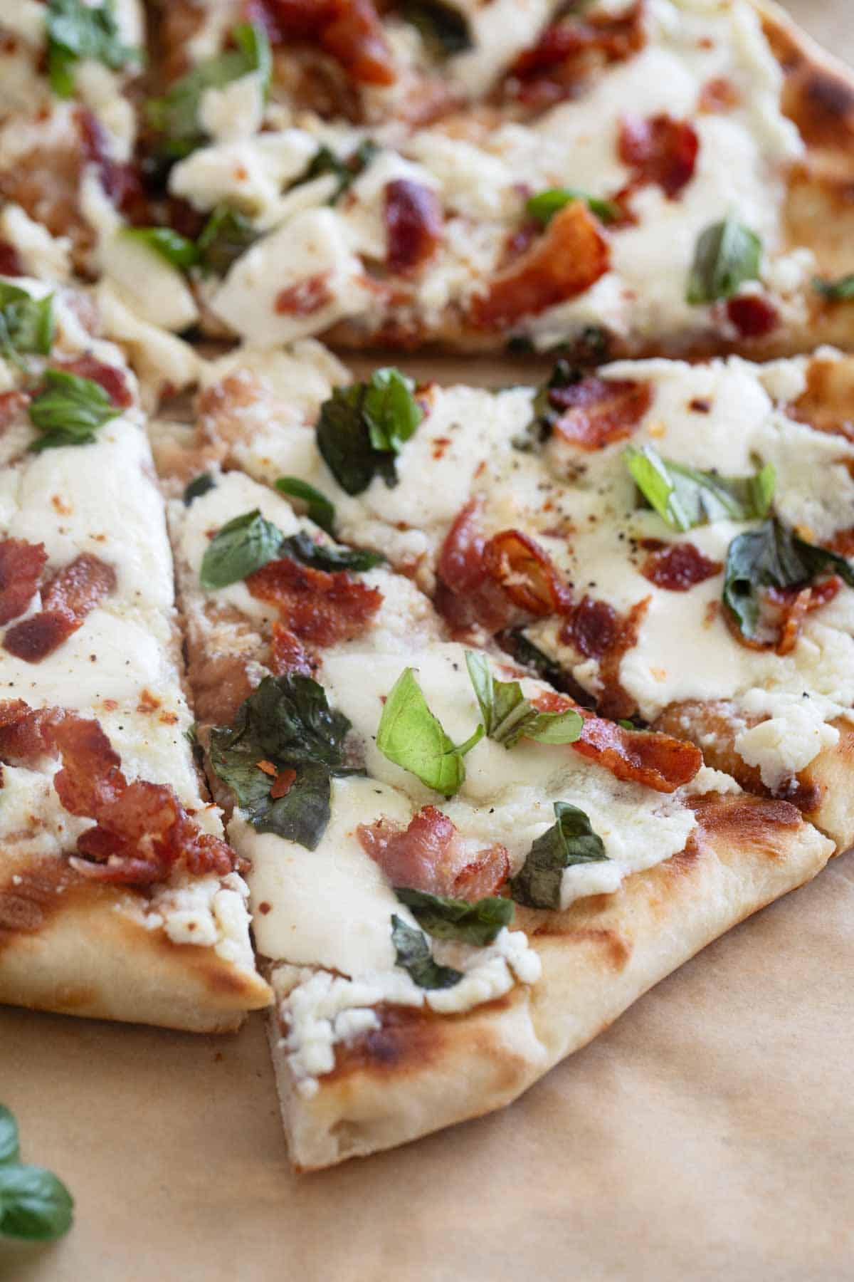 Grilled White Pizza with Bacon and Basil cut into slices.