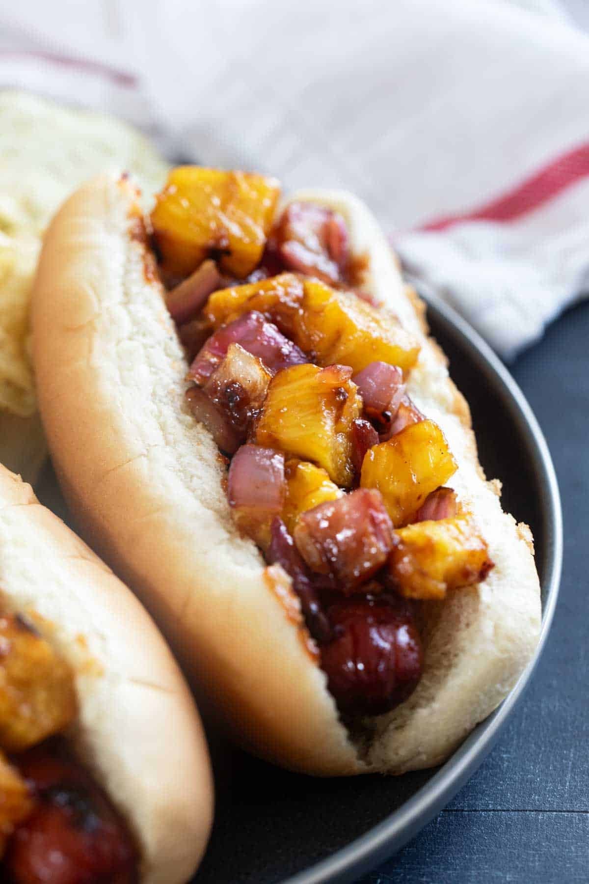 Hawaiian Hot Dogs with grilled pineapple and red onion with barbecue sauce.