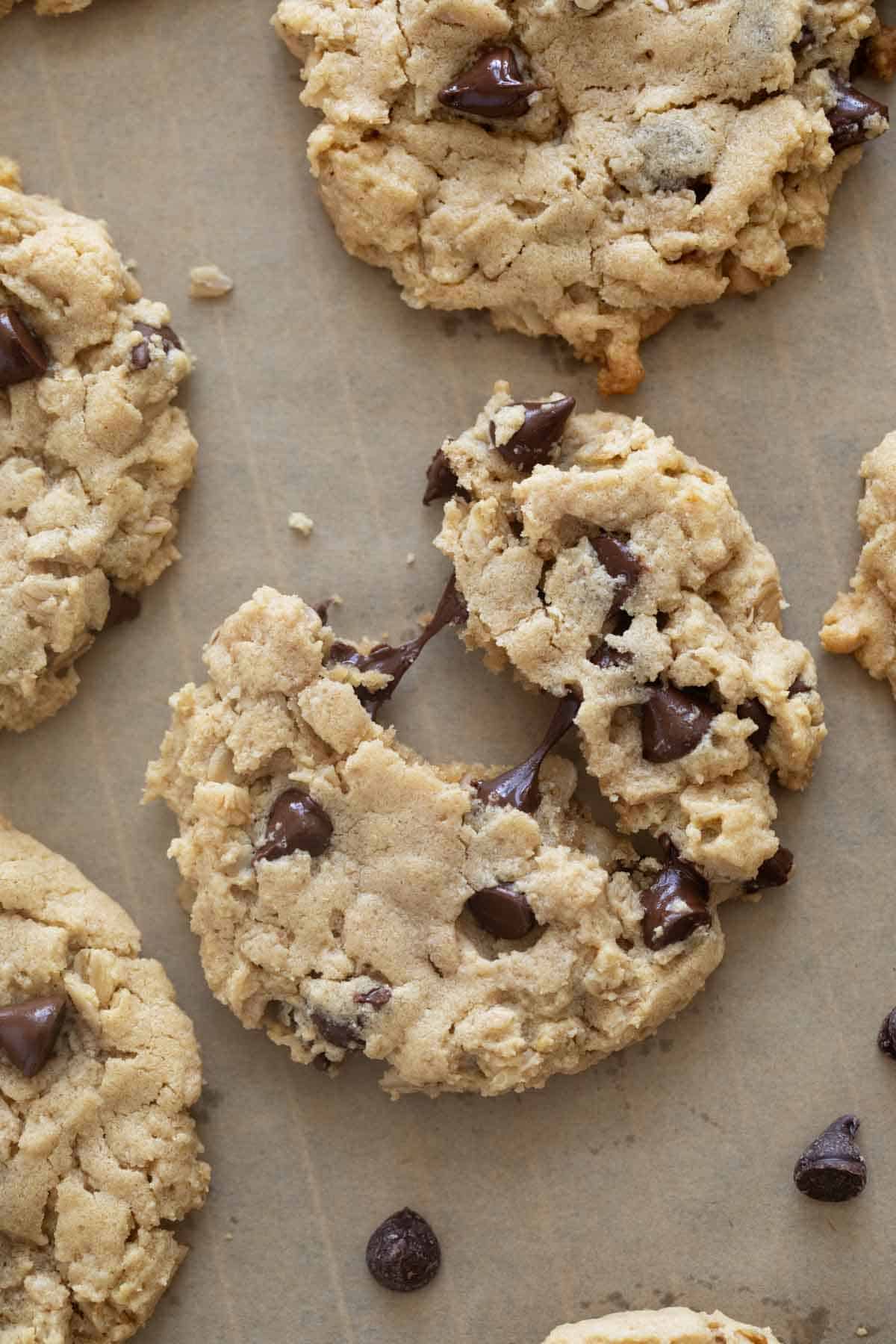 Peanut butter oatmeal cookies with chocolate chips with a cookie broken in half with melted chocolate.